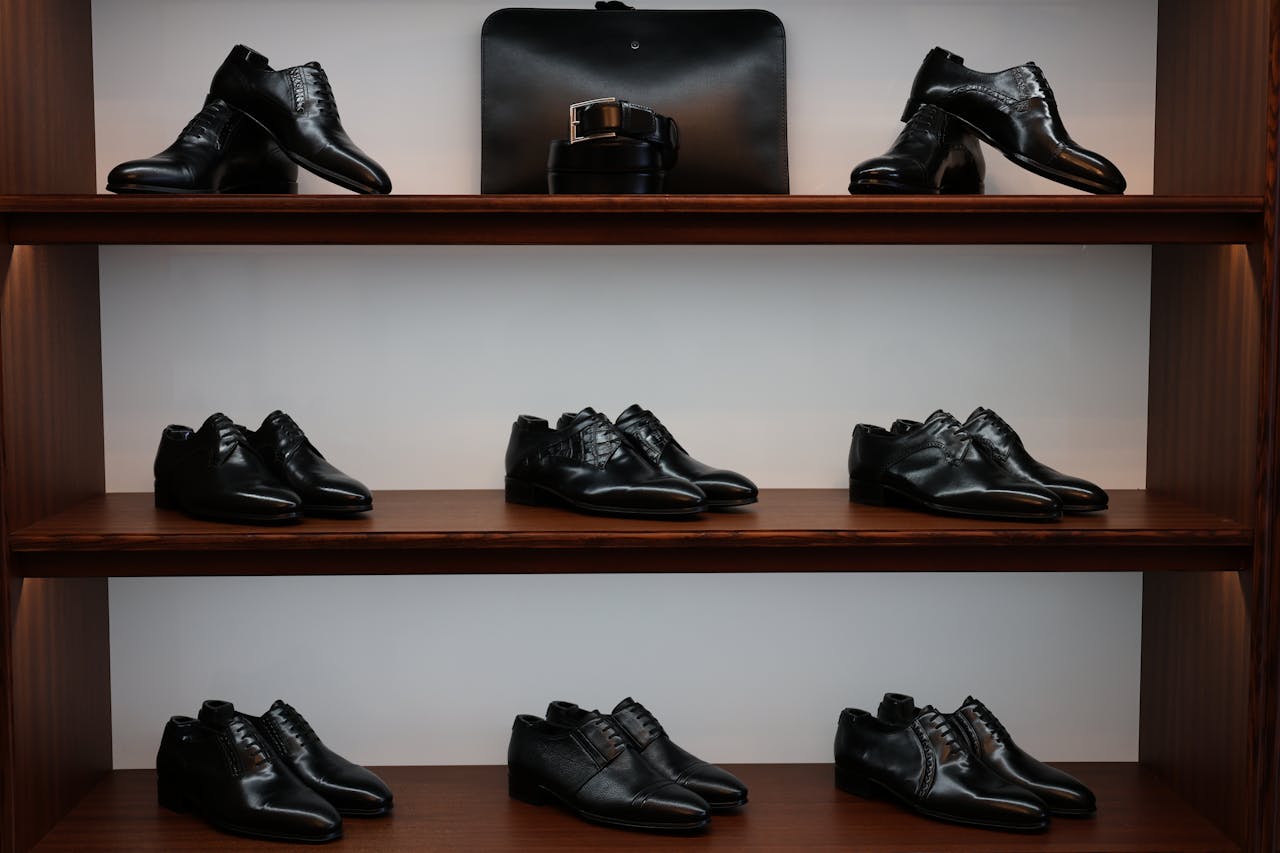 A stylish display of black leather shoes and accessories on wooden shelves in a store.